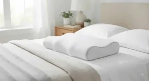 An orthopedic neck support pillow positioned on a bed for optimal back sleeping comfort.